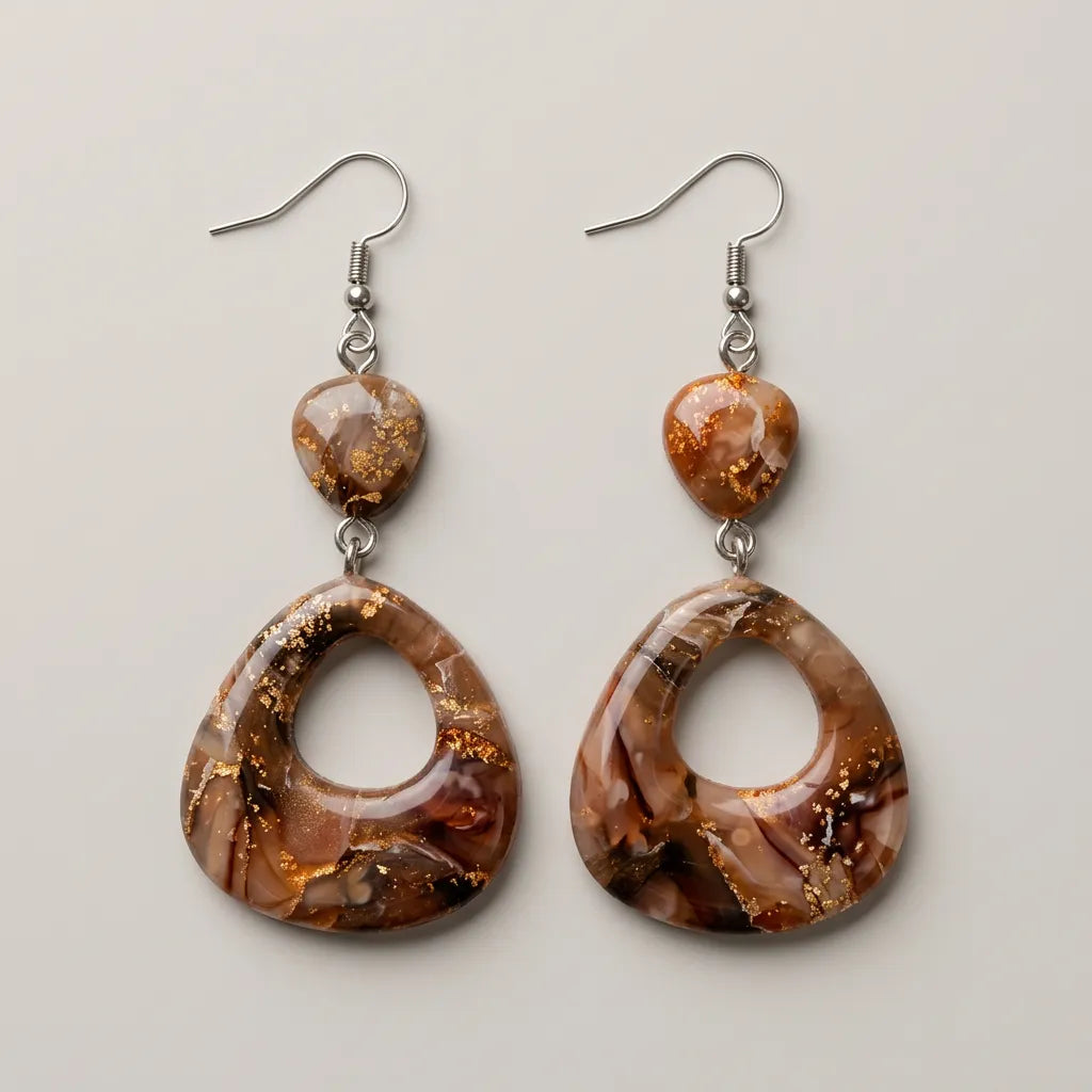 "A pair of Diddit Desert Onyx drop earrings featuring open teardrop pendants and small stone top pieces, both with a rich brown and cream marbled finish with gold fleck detailing, on silver fishhook wires, displayed on a light grey background."
