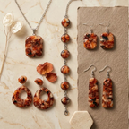"A Diddit Tortoiseshell jewellery collection flat-lay on a light marble surface, featuring a rectangular pendant necklace, a silver chain bracelet with round cabochons, open teardrop drop earrings, square drop earrings, and long rectangular drop earrings, all crafted from marbled orange, cream, and black tortoiseshell patterned stone with silver-tone findings, styled with dried flowers and petals."